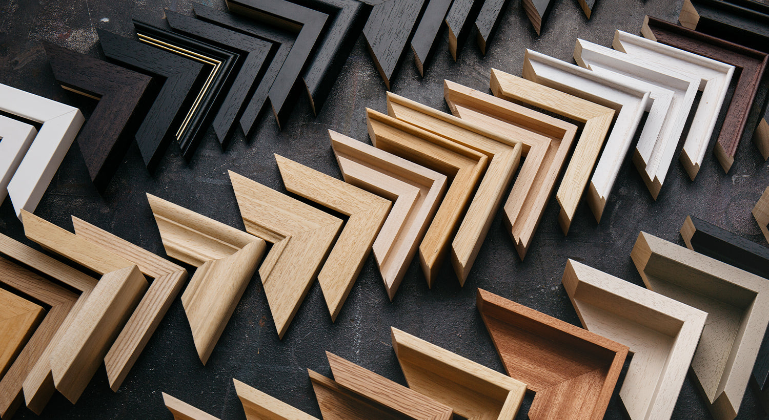 Collection of wooden frames in various sizes and colours on a dark surface,